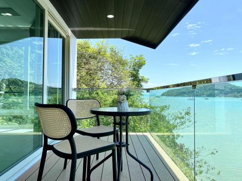 a table and chairs on a balcony with a view of the water at Seaview Duplex Home - Panwa Beach - Baan Jayden in Phuket