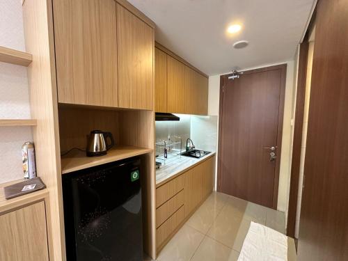 a kitchen with wooden cabinets and a black appliance at Apartment Nagoya Thamrin favehotel in Nagoya