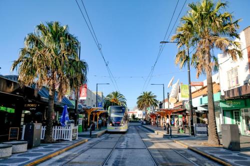 un tranvía conduciendo por una calle de la ciudad con palmeras en St Kilda Accommodation, en Melbourne