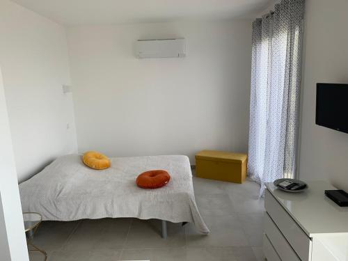 - une chambre dotée d'un lit avec deux oreillers orange dans l'établissement Studio village Brando Cap-Corse, à Brando