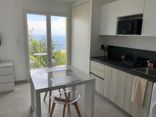 une cuisine avec une table et un comptoir avec une fenêtre dans l'établissement Studio village Brando Cap-Corse, à Brando