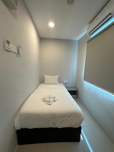 a small room with a bed with a white blanket at Georgetown Hotel in George Town
