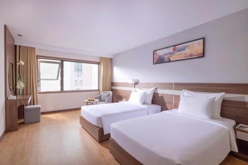 a hotel room with two beds and a chair at PANAMA Nha Trang Hotel in Nha Trang