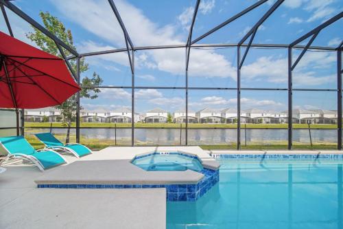 a pool with a red umbrella and chairs and a swimming pool at The Bling Estate in Kissimmee