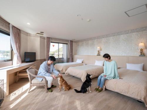 two people and two dogs in a bedroom with two beds at Wan Wan Paradise Hamanako in Hamamatsu