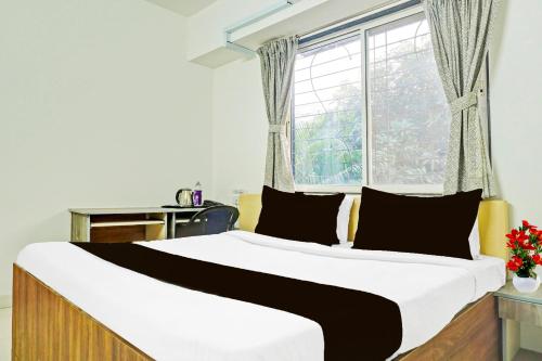 a bedroom with a large bed with a window at Super Collection O Baner formerly Seven Hills in Pune