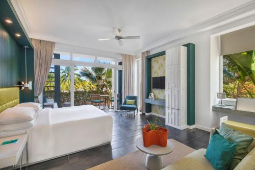 a bedroom with a white bed and a living room at Long Beach Mauritius in Belle Mare