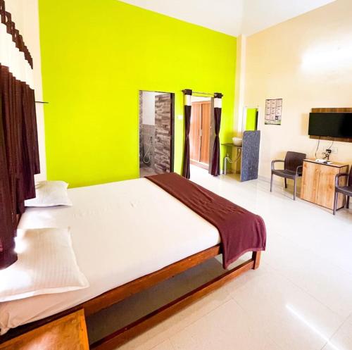 a bedroom with a large bed with a green wall at Madhura Agro Tourism in Wai