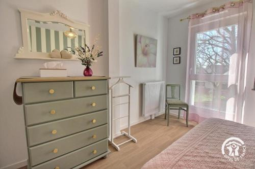 a bedroom with a green dresser and a mirror at Le clos du ponant in Ploeren