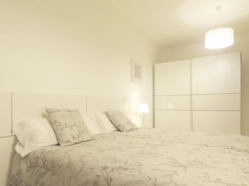a white bedroom with a large white bed with pillows at Pension Mayte in Pamplona