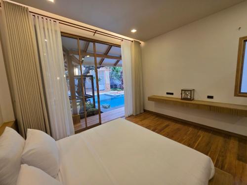 una camera da letto con un letto e una grande finestra di Baan Prod Pool Villa Chiang Mai a Chiang Mai