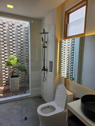 bagno con servizi igienici e finestra con pianta di Baan Prod Pool Villa Chiang Mai a Chiang Mai