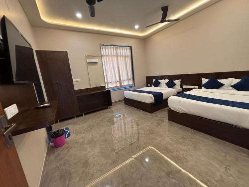 a hotel room with two beds and a television at Hotel Sisodiya Palace in Khātu