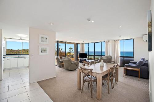 a living room with a table and chairs at Pacific Towers Beach Resort in Coffs Harbour