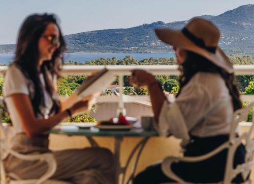 two women sitting at a table reading a book at Hotel Corsica & Spa Serena in Calvi