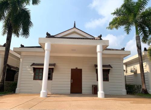 a white house with palm trees in front of it at Hawaii Beach Bungalows in Sihanoukville