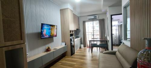 a living room with a couch and a tv on a wall at Classy! 2BR Apartment - Modern Comfort in West Jakarta CBD in Jakarta