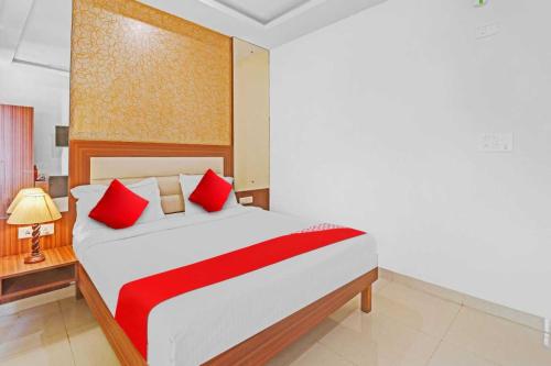 a bedroom with a large bed with red pillows at Hotel O Jakksandra Formerly Harsha Boarding in Mālūr