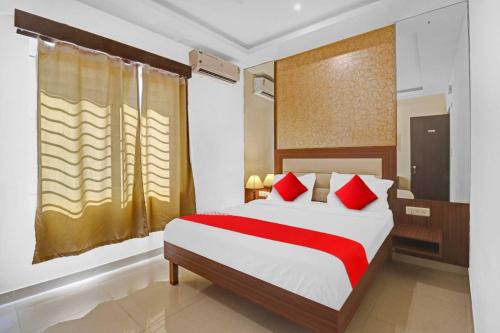 a bedroom with a large bed with red pillows at Hotel O Jakksandra Formerly Harsha Boarding in Mālūr