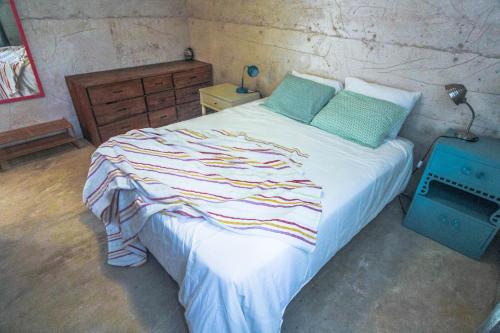 a bedroom with a large bed with white sheets and green pillows at Todos Santos Hostel super fast and stable satellite wifi in Todos Santos