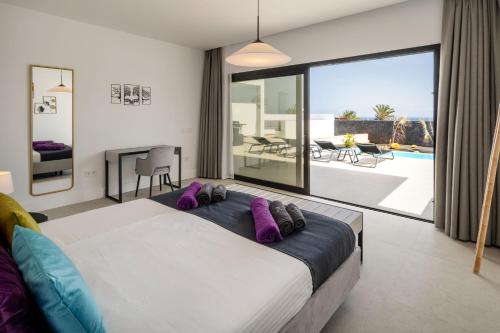 a bedroom with a large bed with purple pillows at ODIN VILLAS by Buenavilla in Puerto Calero