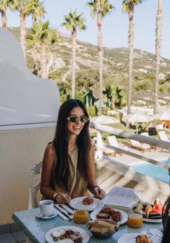 a woman sitting at a table with a plate of food at Hotel Corsica & Spa Serena in Calvi