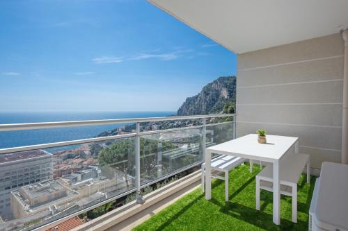 a balcony with a white table and a view of the ocean at JARDINS DE MONACO - Vue Mer - Jacuzzi - Parking in Cap d'Ail