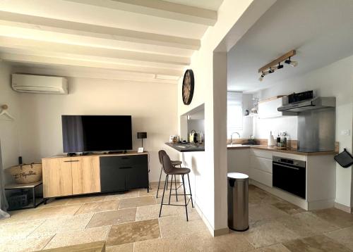 une cuisine avec une télévision et un comptoir avec un tabouret dans l'établissement L'ALPILLE - Maison de vacances située à 10 mn à pied du centre ville de St Rémy avec place de parking privative, à Saint-Rémy-de-Provence