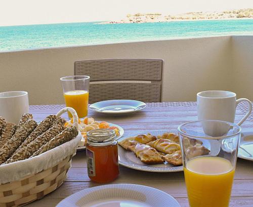 Una mesa con un plato de comida y jugo de naranja. en Lily of Crete 1 - Sea & Beach front Apartment, en Kalamaki