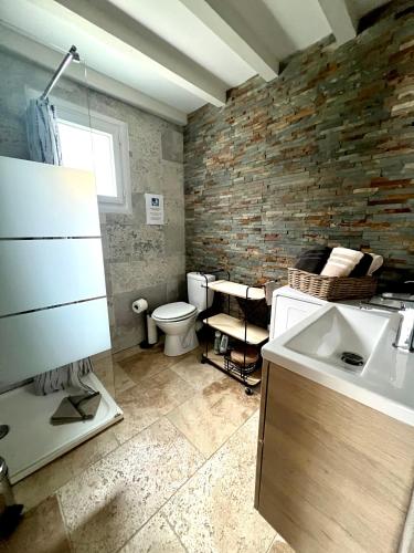 La salle de bains est pourvue d'un lavabo et d'un mur en briques. dans l'établissement L'ALPILLE - Maison de vacances située à 10 mn à pied du centre ville de St Rémy avec place de parking privative, à Saint-Rémy-de-Provence