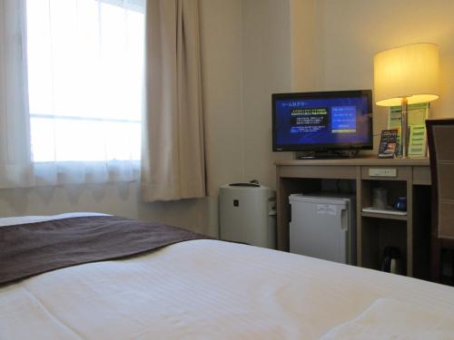 a bedroom with a bed and a flat screen tv at Shin-Osaka Sunny Stone Hotel in Osaka