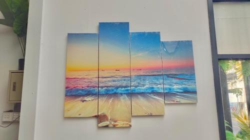 four pieces of the beach paintings on a wall at La Mansion Durian Hotel in Kampot