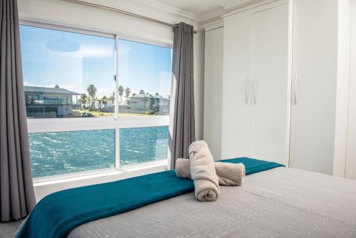 a bed with a towel animal on it in front of a window at 33 Kingston Place, Marina Martinique in Jeffreys Bay