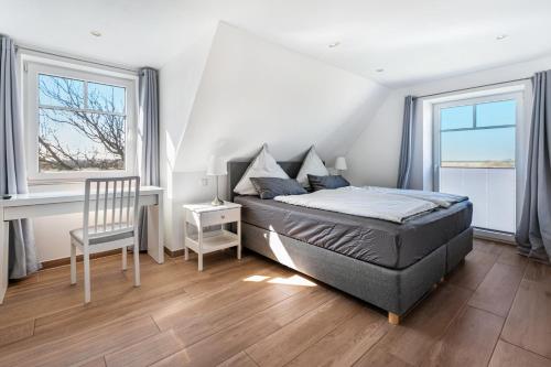 una camera da letto con un letto, una scrivania e due finestre di Haus Am Meer Familie Frener a Pellworm