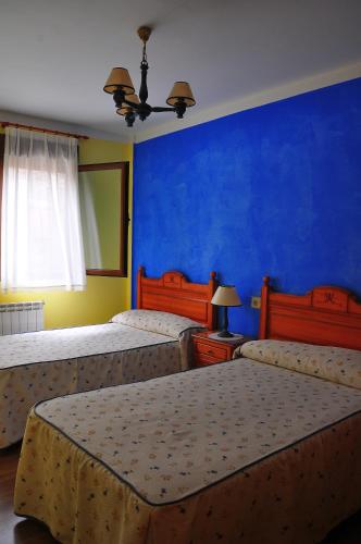 a bedroom with two beds and a blue wall at El Balcón de Onís in La Robellada de Onis
