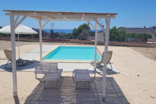 a group of chairs and a swimming pool with an umbrella at Villa Pescoluse with Pool and Sea View - Happy Rentals in Salve