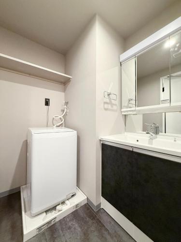 a white bathroom with a sink and a mirror at Lifement - 1min to Peace Park, Modern and Secure Apt in Hiroshima