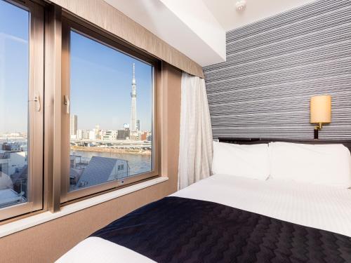a bedroom with a bed and a large window at APA Hotel Asakusa Kuramae in Tokyo