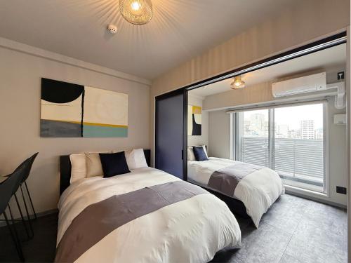 a bedroom with two beds and a window at Lifement - 1min to Peace Park, Modern and Secure Apt in Hiroshima