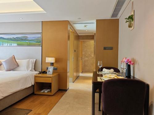 a hotel room with a bed and a desk and a table at Somerset Grandview Shenzhen in Shenzhen