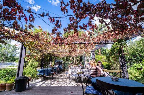 a garden with people sitting at tables under a pergola at The Rustic Nest Yarramalong in Yarramalong
