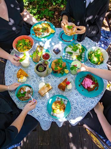 a group of people sitting around a table with food at The Rustic Nest Yarramalong in Yarramalong