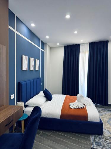 a bedroom with a bed with blue walls and a table at Andor Luxury Hotel & Duplex in Durrës