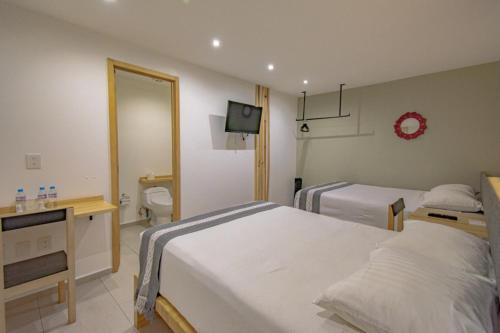 a hotel room with two beds and a bathroom at Capital O Hotel Terraza 158 in Mexico City