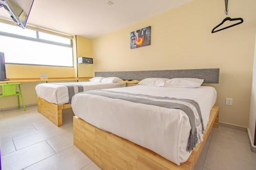 a hotel room with two beds and a window at Capital O Hotel Terraza 158 in Mexico City