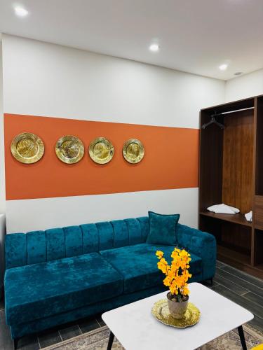 a living room with a blue couch and plates on the wall at Andor Luxury Hotel & Duplex in Durrës