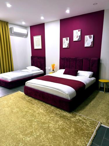 a bedroom with two beds and a purple wall at Andor Luxury Hotel & Duplex in Durrës