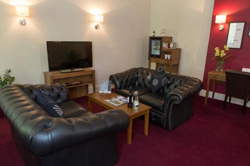 a living room with two leather couches and a tv at The Crown Hotel in Harrogate