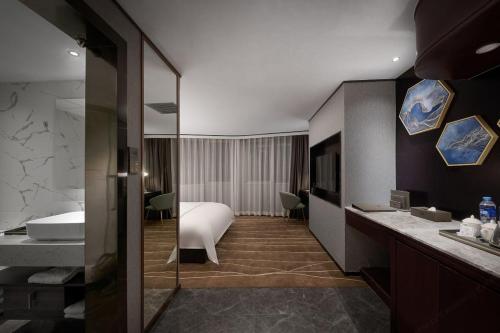 a hotel room with a bed and a bathroom at Guangzhou Wenyue Lihua Hotel in Huadu