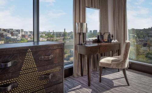 a desk and chair in a room with a window at Doubletree By Hilton London - Greenwich in London
